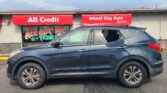 Blue SUV parked in front of a storefront with red All Credit and Wheel City Auto signs on the awnings. The window displays graphics reading 'We Accept All Trade'.