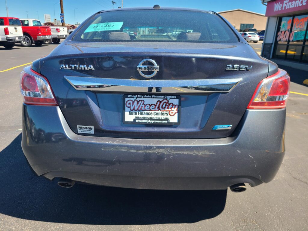 Rear view of a black Nissan Altima 2.5 SV in a car lot, with a Wheel City license plate frame and a dealership window sticker visible on the rear windshield.