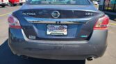 Rear view of a black Nissan Altima 2.5 SV in a car lot, with a Wheel City license plate frame and a dealership window sticker visible on the rear windshield.