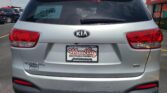 Rear view of a silver Kia SUV at a dealership, with Wheel City Auto Finance Centers signage on the license plate frame and a green sale sticker in the rear window.