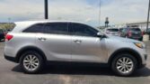 Side view of a silver SUV in a parking lot, with other cars and a building in the background.