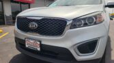 Front view of a silver Kia SUV parked at a Wheel City Auto dealership, showing the grille, headlights, and Wheel City license plate frame