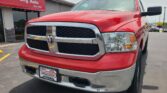 Close-up of a red pickup truck front end in a dealership lot, with a Wheel City Auto sign in the background.