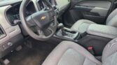 Interior of a car focusing on the driver's side: steering wheel, instrument cluster, center console, and gray fabric seats.
