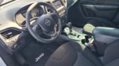 Jeep interior with steering wheel, central touchscreen, and gear shift seen from the passenger side start area.