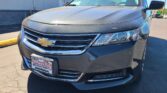 Front of a dark Chevy SUV with chrome grille, partial windshield, and a dealer plate reading 'Wheel City Auto Finance Centers' visible on the bumper.