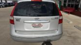 Rear view of a silver Hyundai Touring minivan parked at a car dealership, with a Wheel City Auto Finance Center license plate frame visible on the back.