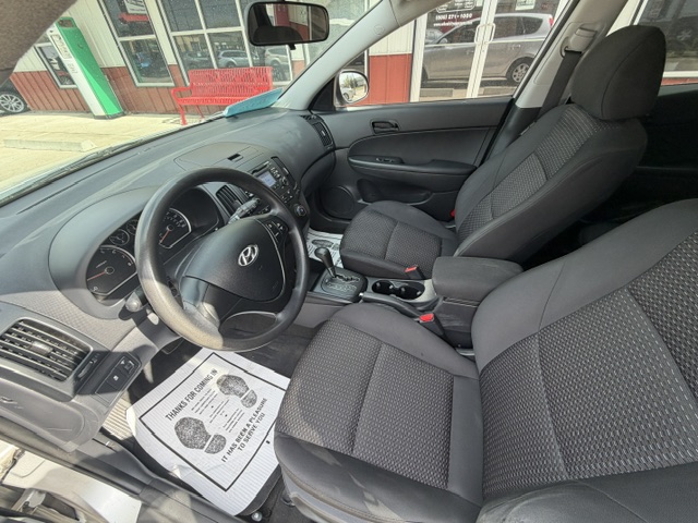Interior of a dark-gray Hyundai sedan showing the front seats, steering wheel, dashboard, and center console