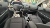 Interior view of a left-drive car showing the dashboard, steering wheel with Hyundai logo, center console, and front seats.