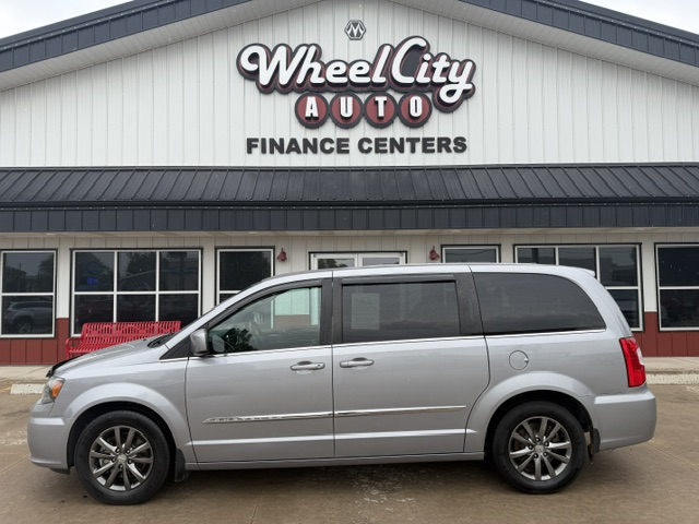 Silver minivan parked in front of Wheel City Auto Finance Centers dealership, with the storefront and large sign visible.