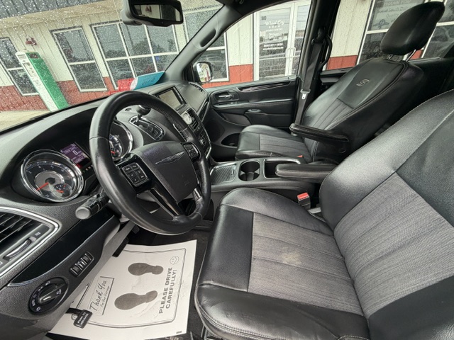 Front interior of a dark pickup truck: driver and passenger seats, steering wheel, center console, and floor mat with a thank-you note visible on the driver's side.