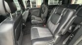 Interior of a dark leather SUV/minivan with three rows of seats, including middle-row captain's chairs and rear bench.