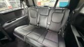 Black leather rear bench seat in an SUV, showing three seating positions and built-in cupholders on the left side