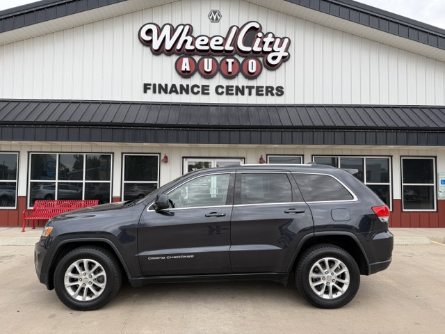 Dark gray Jeep Grand Cherokee SUV parked in front of Wheel City Auto Finance Centers storefront sign(s).