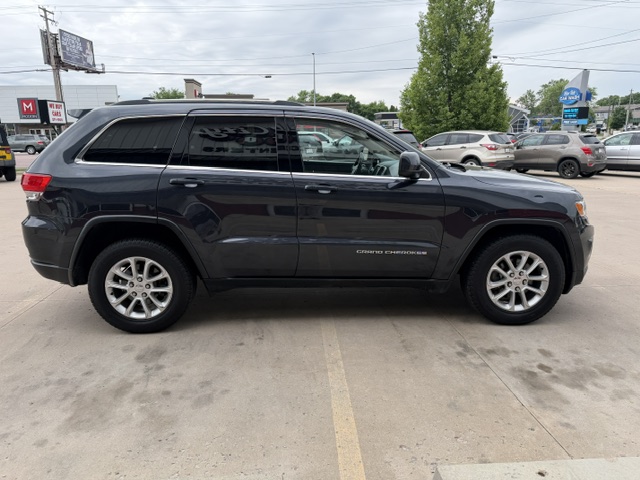 Side view of a black Jeep Grand Cherokee SUV parked in a lot, with tinted windows and alloy wheels visible.