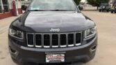 Front view of a black Jeep SUV parked in a dealership lot with a Wheel City license plate frame on the bumper