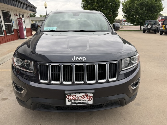 Front view of a black Jeep SUV parked in a dealership lot with a Wheel City license plate frame on the bumper