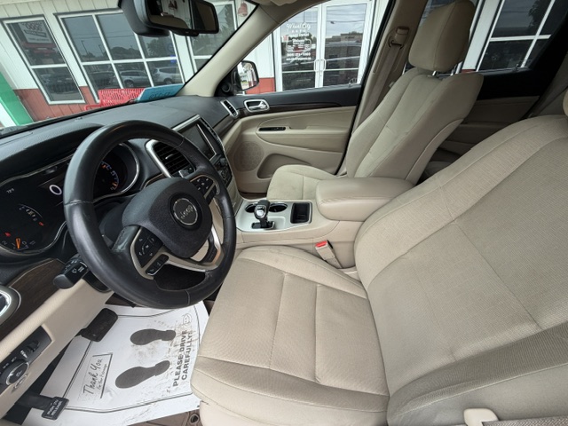 Interior of a beige SUV: steering wheel, dashboard, and front seats visible from the driver's side, center console with gear shifter in view