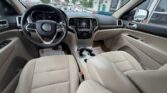 Beige interior of a Jeep SUV seen from the driver’s seat, showing the steering wheel, center touchscreen, gear shifter, and front seats.