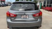 Rear view of a silver Mitsubishi Outlander Sport SUV in a dealership lot, with a Wheel City Auto Finance Centers license plate frame.