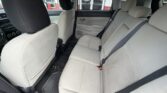 Rear bench in a sedan with light gray cloth seats and three seat belts, front seats visible as well as door panel.