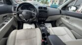 Front interior of a beige-clad Mitsubishi sedan, showing steering wheel, center console, and two front seats viewed from the back seat area.