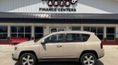 Beige SUV parked in front of a Wheel City Auto Finance Centers storefront with a red bench to the left.