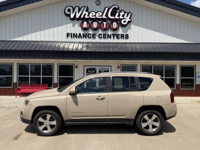 Beige SUV parked in front of a Wheel City Auto Finance Centers storefront with a red bench to the left.