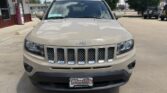 Beige Jeep SUV photographed from the front in a dealership lot with a seven-slot grille and Wheel City license plate frame on the bumper.