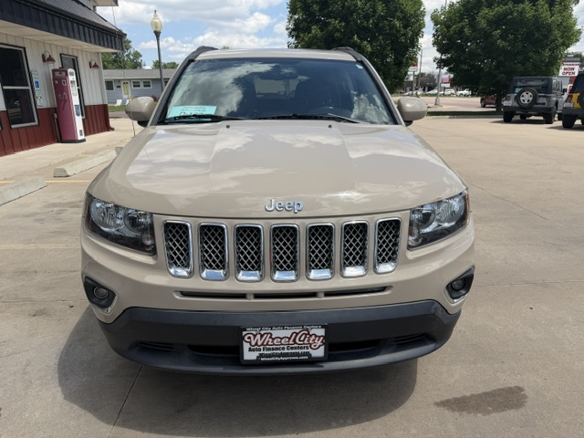 Beige Jeep SUV photographed from the front in a dealership lot with a seven-slot grille and Wheel City license plate frame on the bumper.