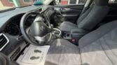 Interior of a car from the driver's side, showing steering wheel, dashboard, center console, and front seats.