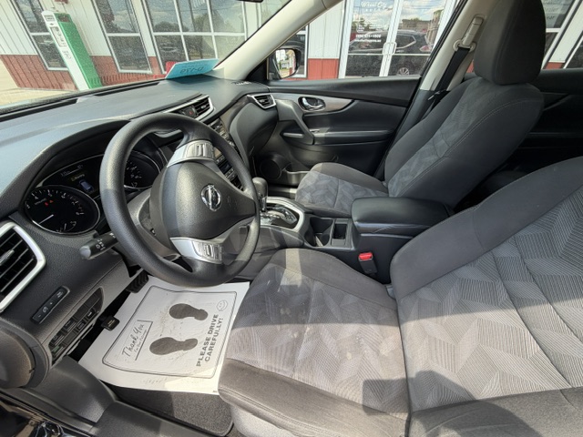 Interior of a car from the driver's side, showing steering wheel, dashboard, center console, and front seats.