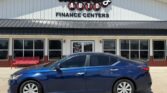 Blue sedan parked in front of Wheel City Auto Finance Centers storefront, dealership sign visible above.