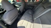 Rear seat of a gray fabric car, three-seat bench with seat belts; front seats and door panels visible in the cabin.