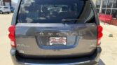 Rear view of a gray Dodge Grand Caravan parked at a dealership, with a Wheel City Auto Finance Centers license plate frame visible.