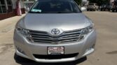 Front view of a silver Toyota sedan in a dealership lot, with a Wheel City license plate frame visible on the bumper.