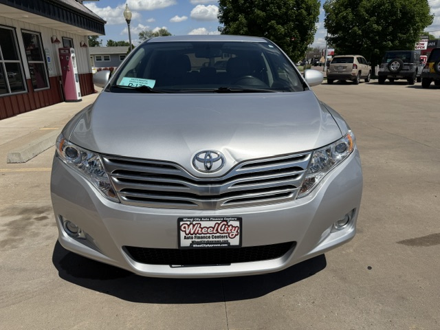 Front view of a silver Toyota sedan in a dealership lot, with a Wheel City license plate frame visible on the bumper.