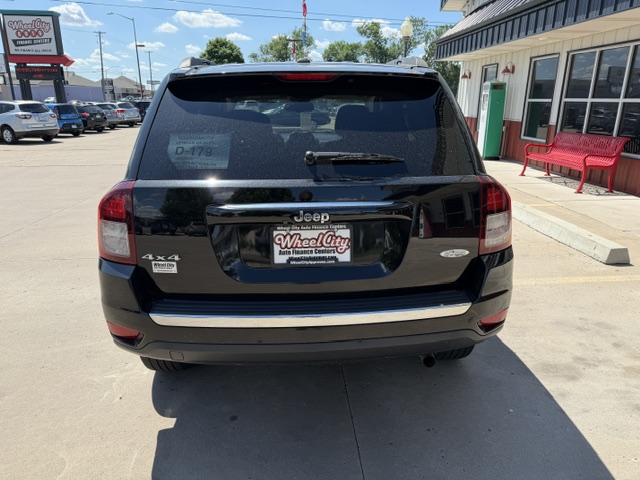 Rear view of a black Jeep SUV in a dealership lot, showing 4x4 badge and dealer plate frame reading Wheel City Auto Finance Centers.