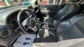 Front interior of a black leather SUV with steering wheel, dashboard, center console, and paper floor mat on the driver's side.