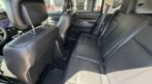 Back seat of a black leather car with three seats and visible headrests; cup holders and center area between the front seats are visible.