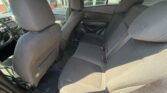 Rear interior of a dark cloth-seated car showing bench back seat with three seat belts and front seats visible from the back door.