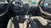 Front interior of a Chevrolet car, seen from the back seat: steering wheel, center console with radio, gear shifter, and front seats in daylight.