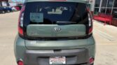 Rear view of a green Kia Soul in a car dealership lot, showing the Kia badge, 'SOUL' lettering, rear windshield wiper, and WheelCity license plate frame.