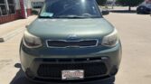 Front view of a green Kia Soul parked at a dealership, with a Wheel City license plate frame on the bumper.