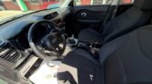 Front interior of a car showing the driver's seat, front passenger seat, steering wheel, manual gear shifter, and center console with dashboard controls.