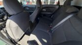 Interior of a car showing the front seats and a rear bench with three seat belts; black cloth upholstery and sunlit cabin.