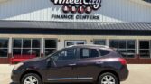 Brown SUV parked in front of Wheel City Auto Finance Centers dealership, with large storefront sign and glass doors under a blue sky.