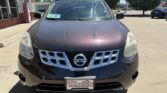 Front view of a dark purple Nissan SUV parked in a dealership lot; chrome grille with Nissan badge and a windshield sticker, Wheel City license plate frame.
