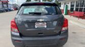 Rear view of a gray Chevrolet Trax LT AWD at a dealership, with a Wheel City license plate frame and window sticker visible on the rear window.