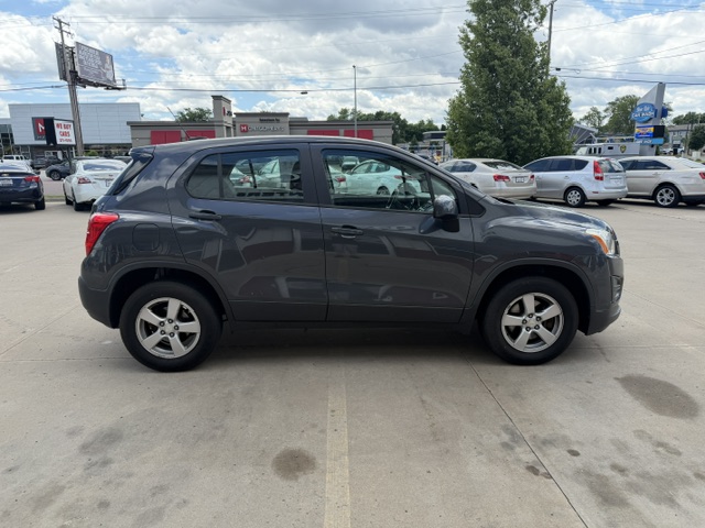 Side view of a dark gray SUV parked in a lot with other cars nearby, under a partly cloudy sky.